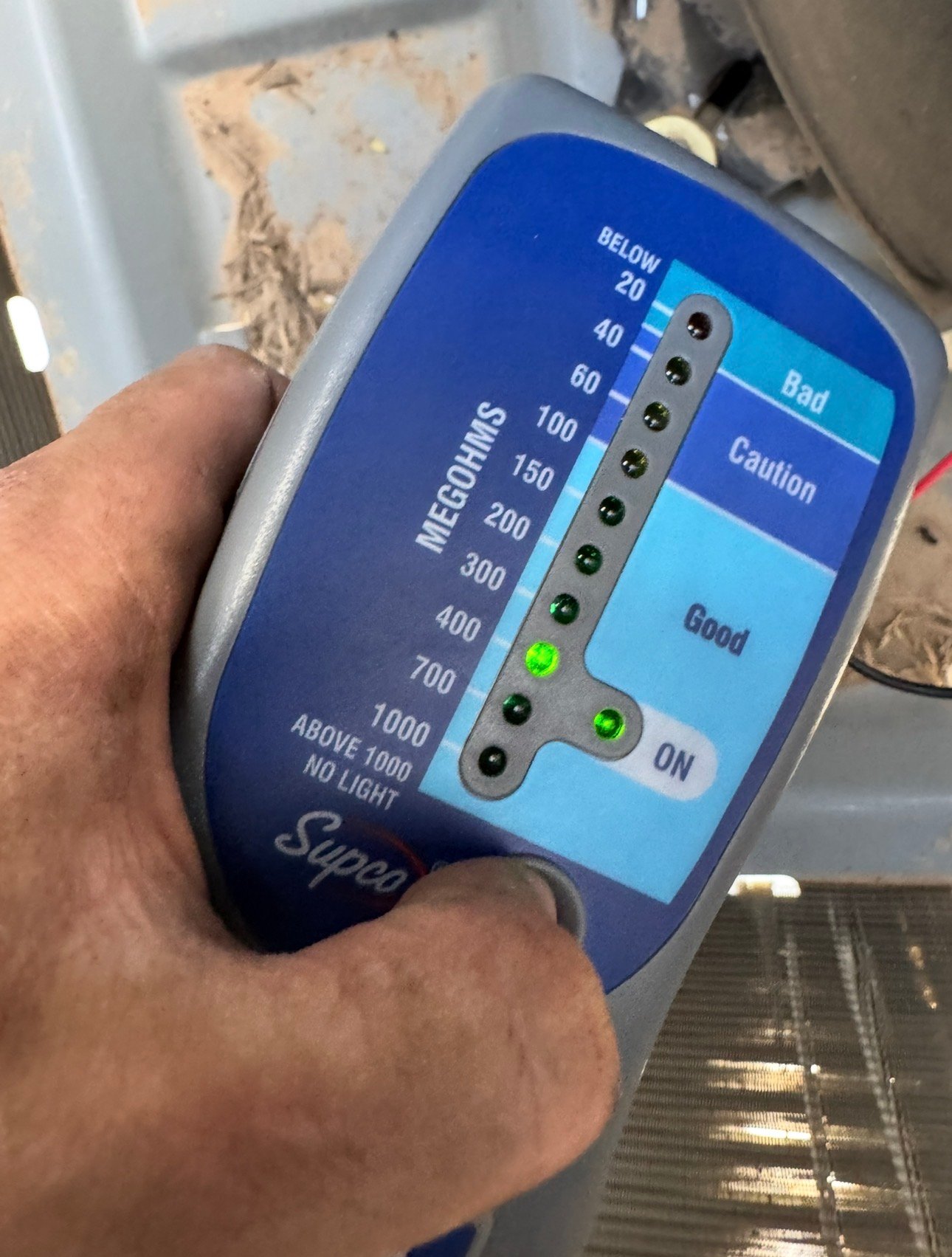 Technician performing megohmmeter testing on a Tucson HVAC system showing good insulation readings