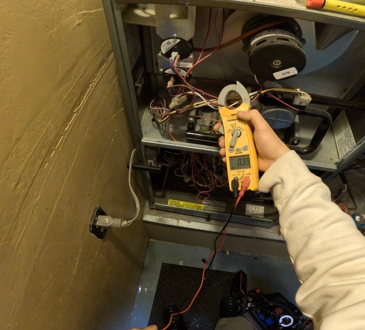 Technician measuring inducer motor amp draw during HVAC service in Oro Valley