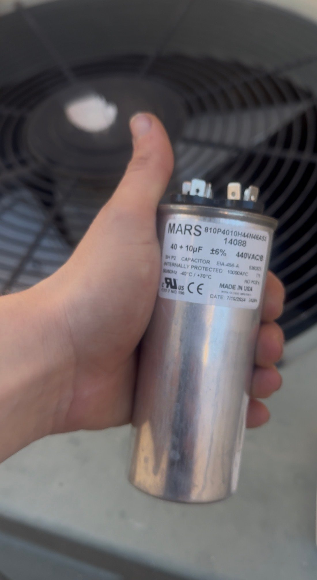 HVAC technician inspecting a capacitor during AC repair in Oro Valley, AZ