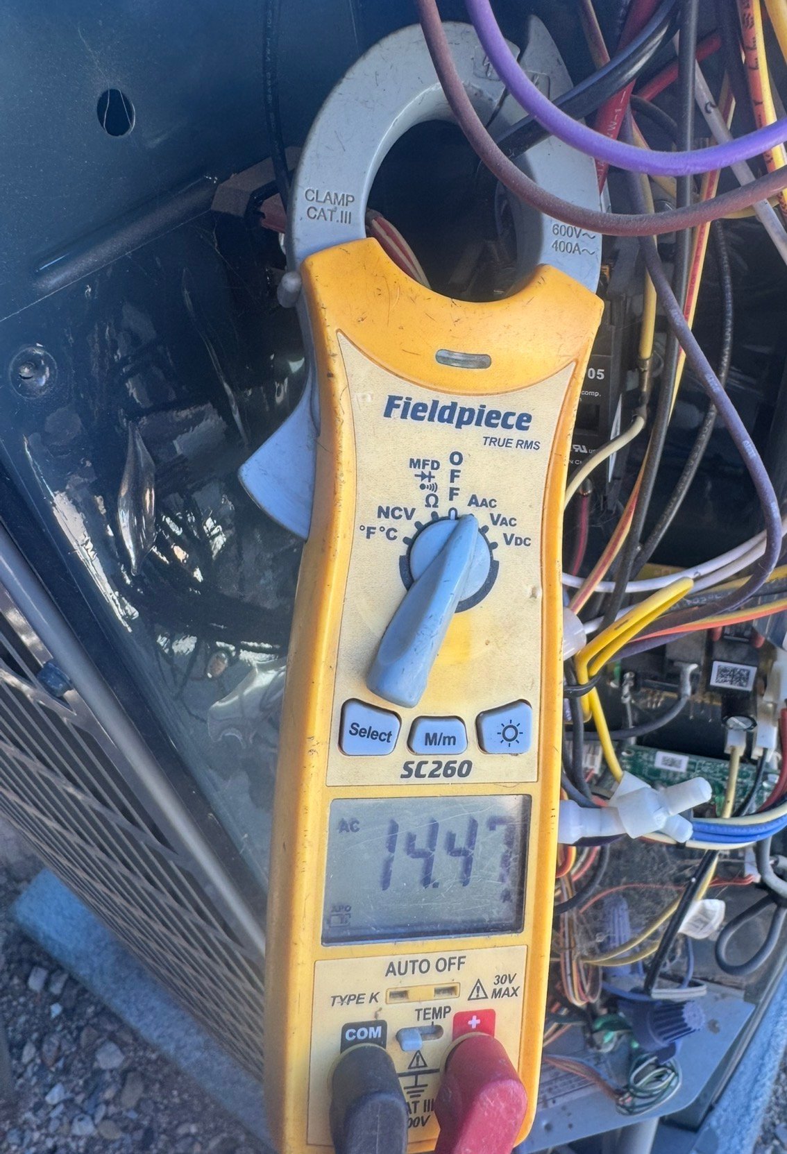 Technician measuring compressor amp draw during AC service in Drexel Heights, AZ